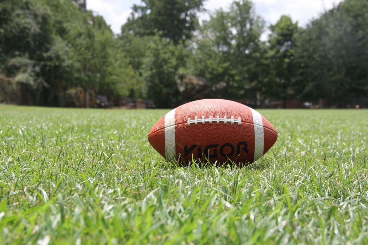 An American football resting on green turf